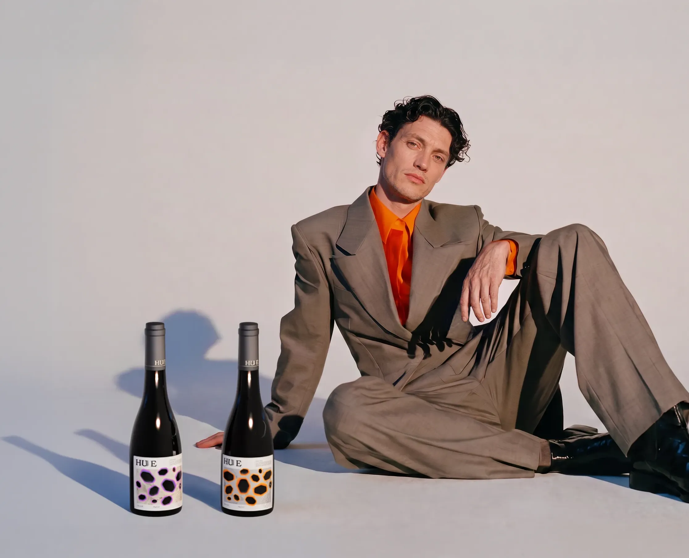 Model in a grey suit posed beside two bottles of HUE English wine